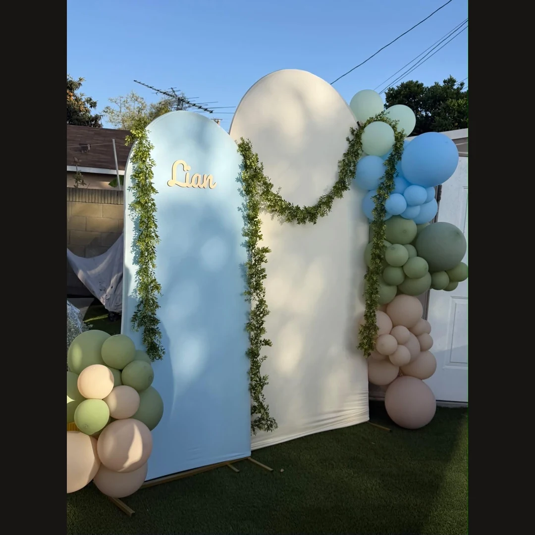 Blue and cream arches with gold Liam lettering, greenery and sage, blue and nude balloons