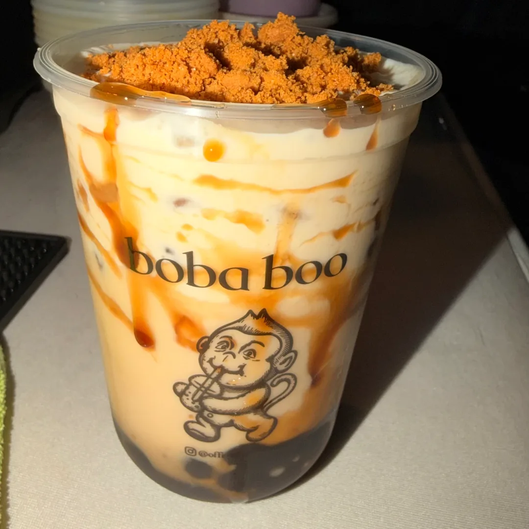 Caramel-lined milk tea with boba pearls and a pile of cookie crumbs on top