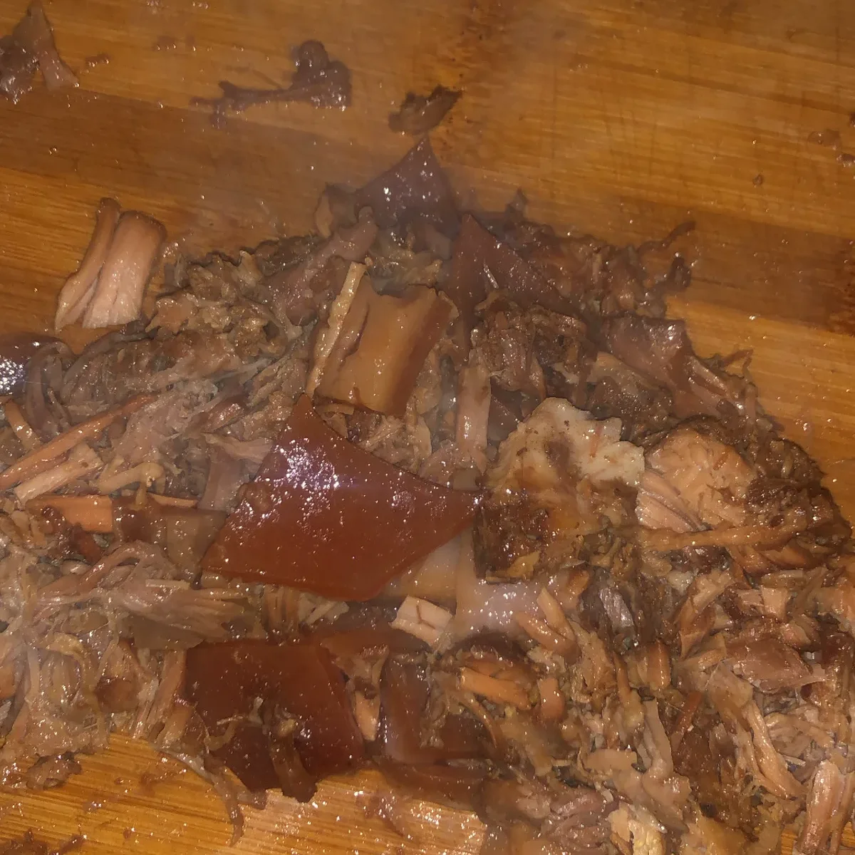 Steaming shredded pork and crispy pork rind resting on a wooden cutting board