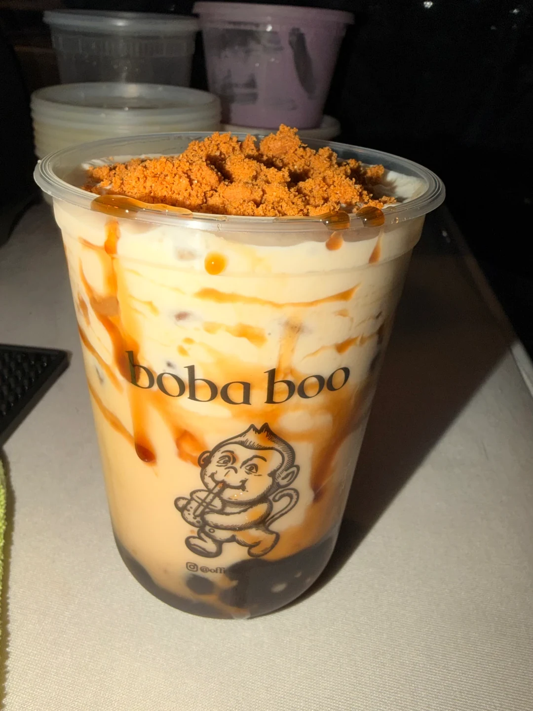 Boba Boo caramel milk tea with cookie crumble topping, caramel drizzle and boba pearls in a branded cup