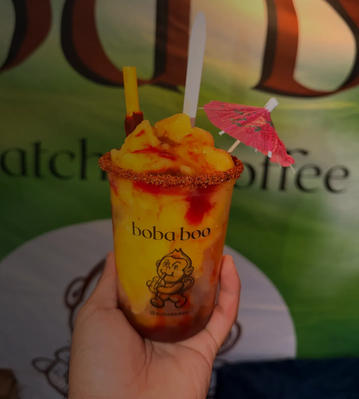 Boba Boo Beverage Bar: Hand holding a Boba Boo mango chamoy slush with a chili-lime rim, pink umbrella and chili-tamarind straw