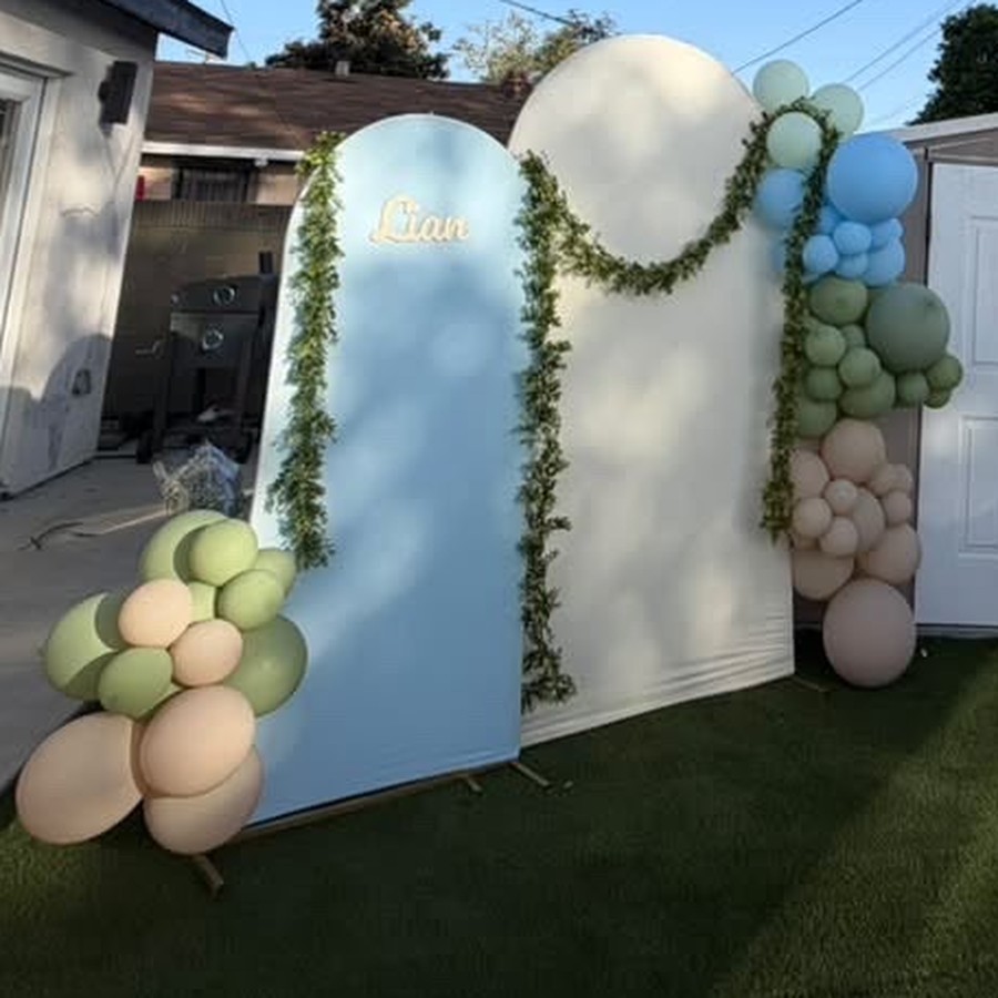 Blue and cream balloon arches with a flower-filled baby pram at a backyard baby shower