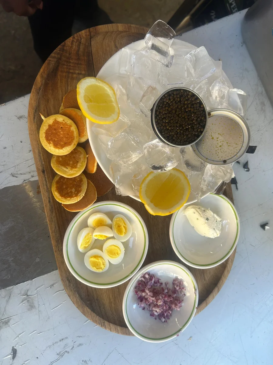 Caviar on ice with blini, lemon, eggs, cream and chopped red onion
