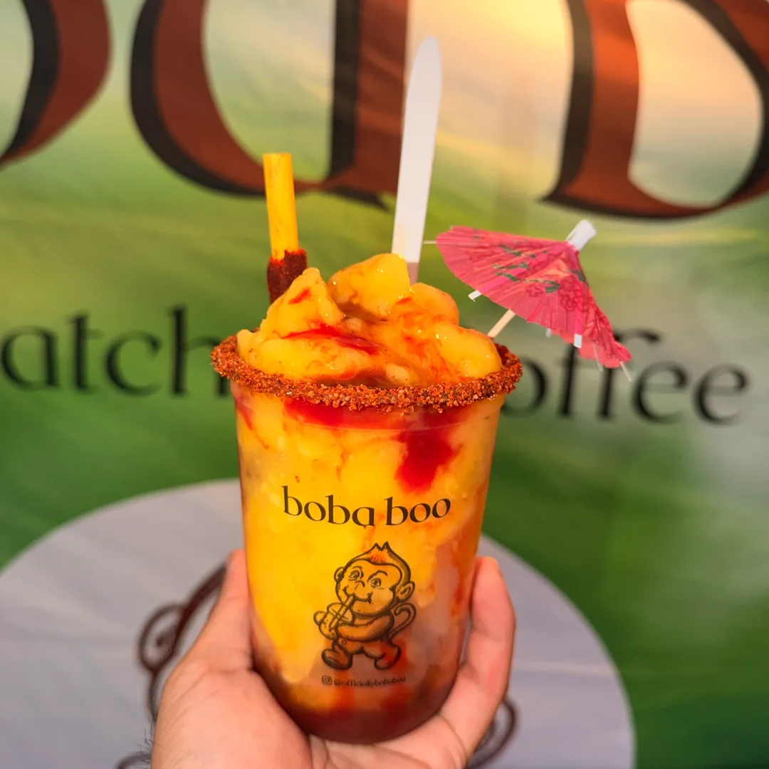 Hand holding a Boba Boo mango chamoy slush with a chili-lime rim, pink umbrella and chili-tamarind straw