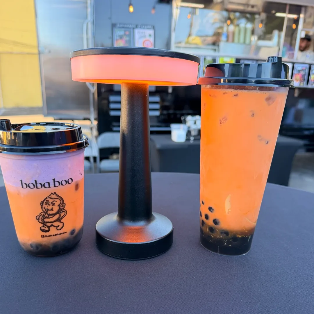 Two Boba Boo drinks beside a glowing black table lamp at the drink truck counter