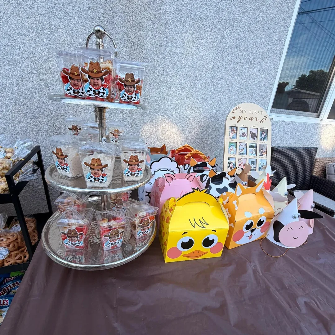 Cowboy-themed party favor table with personalized treat bags and colorful farm-animal boxes