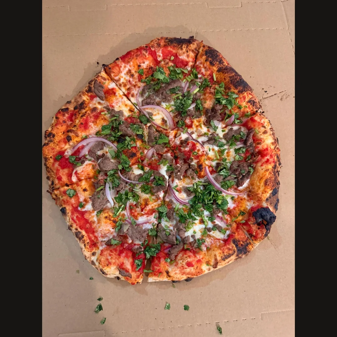 Neapolitan pizza with meat, red onion and fresh herbs