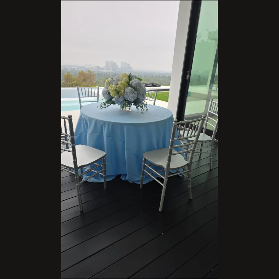 Blue and white floral centerpiece on a blue-draped table beside a pool